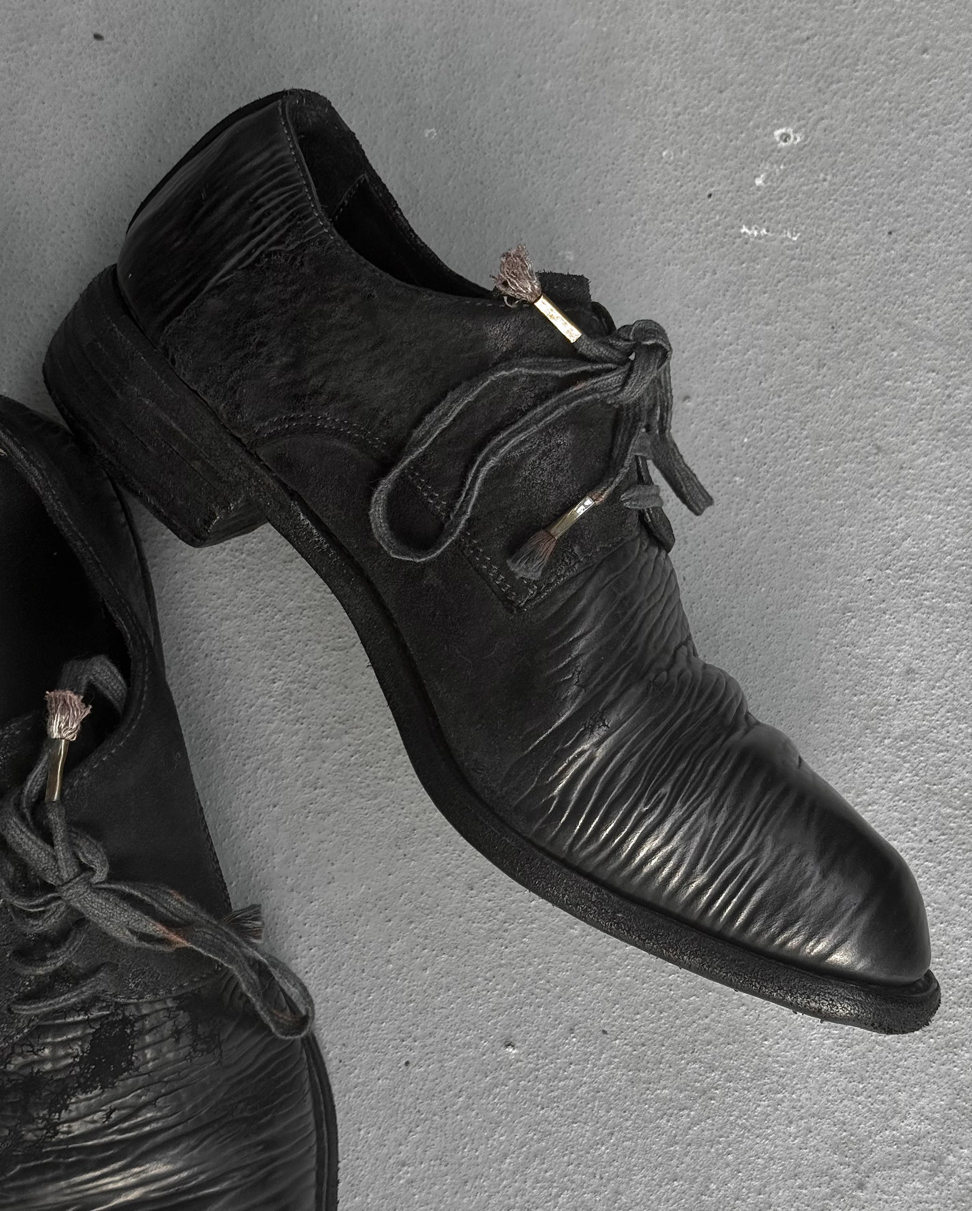 Pair of black leather shoes on a gray surface