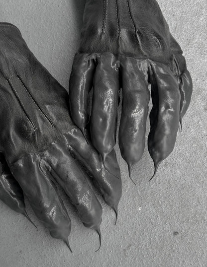 Pair of dark leather gloves with clawed tips on a light gray background