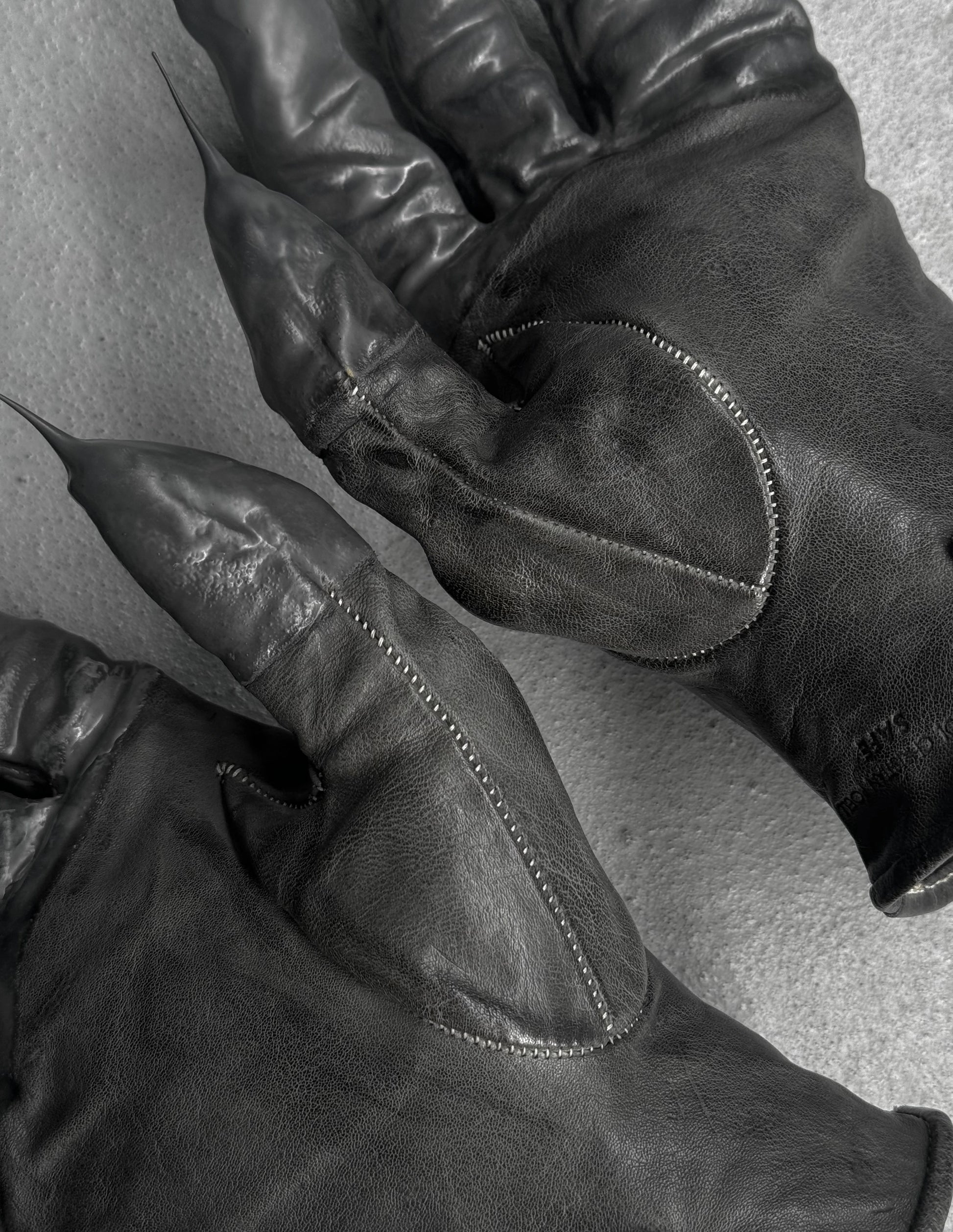 Close-up of black leather gloves with visible stitching on a light background