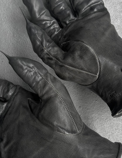 Close-up of black leather gloves with visible stitching on a light background