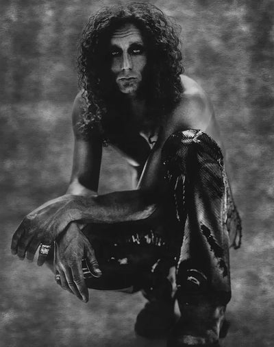 Picture of Chrome Hearts designer Richard Stark crouched down wearing python pants on clear background