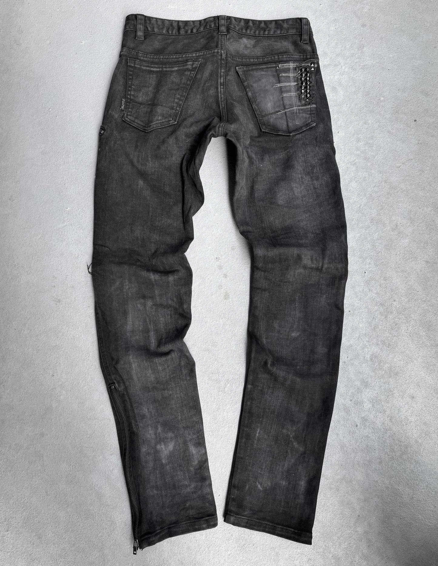 A pair of KMRii Early 00s Goatskin Patches Studded Crush Flare-zip Denim jeans, size 2 (fits US 29-30 waist), black with slight fading, shown from the back with two back pockets and a chain on the right pocket, lies flat on a light grey surface.