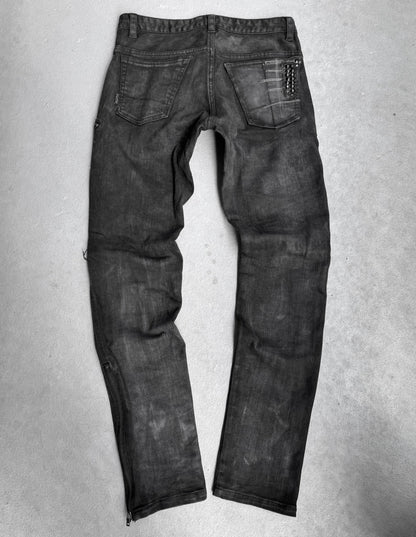 A pair of KMRii Early 00s Goatskin Patches Studded Crush Flare-zip Denim jeans, size 2 (fits US 29-30 waist), black with slight fading, shown from the back with two back pockets and a chain on the right pocket, lies flat on a light grey surface.
