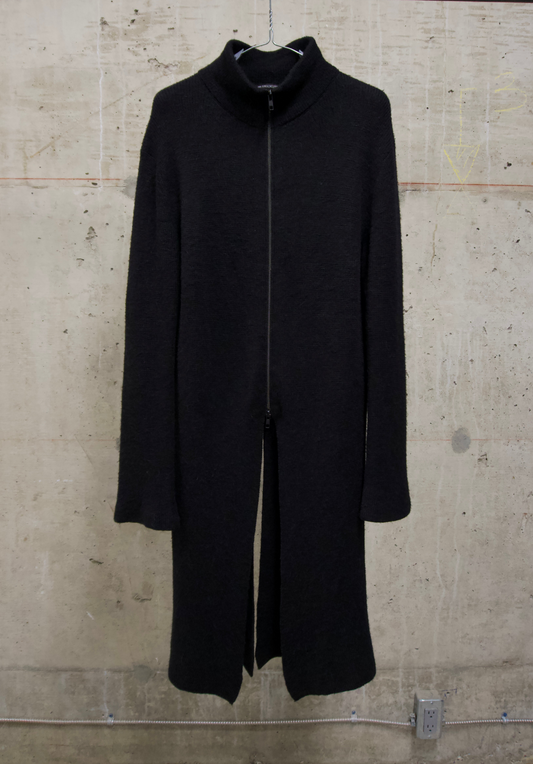 Black coat on a hanger against a textured beige wall