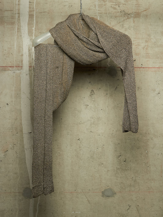 A textured knit scarf in a heathered taupe-brown color, draped over a clear plastic hanger against a concrete wall background.