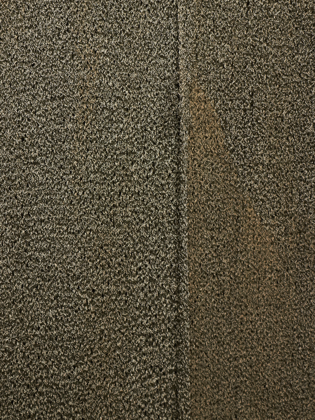 Close-up of a textured carpet or fabric in a mottled dark brown, beige, and gray colorway, showing a vertical seam down the center.