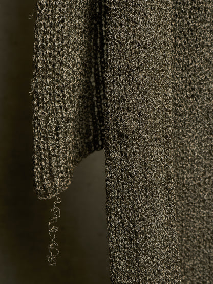 Close-up of a dark metallic textured knit fabric, showing a ribbed sleeve and body with a shimmering bronze and black finish.