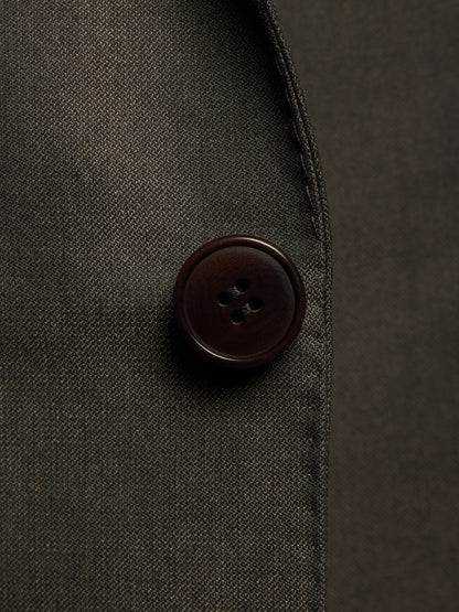 Close-up of a dark brown four-button button on a dark charcoal gray textured fabric garment.