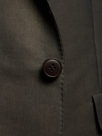 Close-up detail of a dark olive-brown suit jacket showing the texture of the fabric and a single dark brown button.