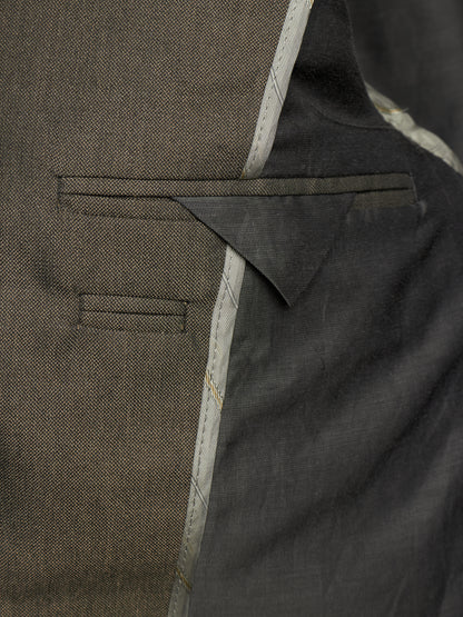 Close-up detail of a tailored jacket or blazer showing a welt pocket, fabric texture, and contrast stitching in dark olive and charcoal tones.