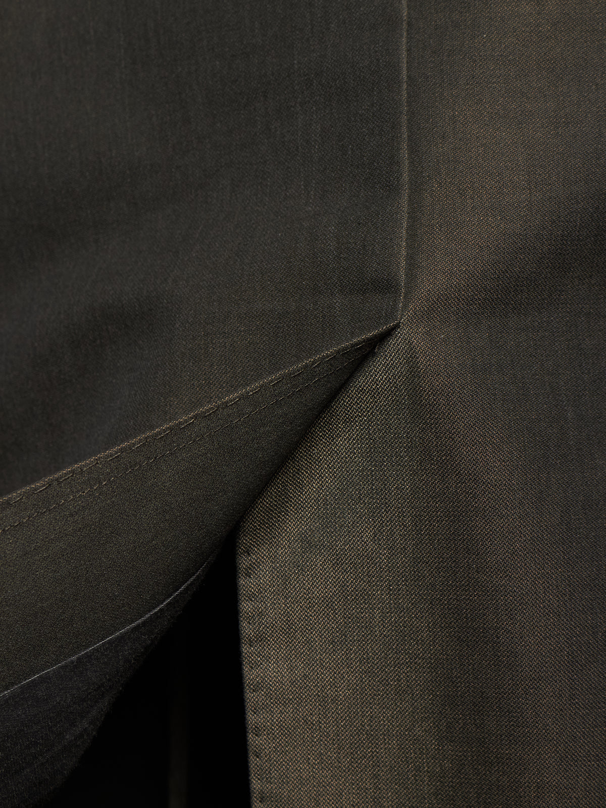 Close-up of dark charcoal gray fabric with a visible fold and stitched seam.