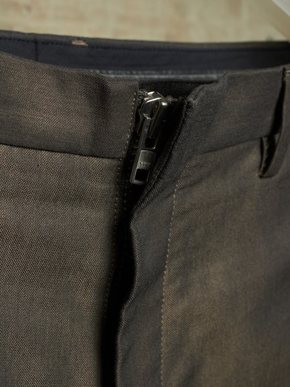 Close-up of a dark charcoal gray zippered garment, likely pants or shorts, showing the fabric texture, waistband, and zipper pull.
