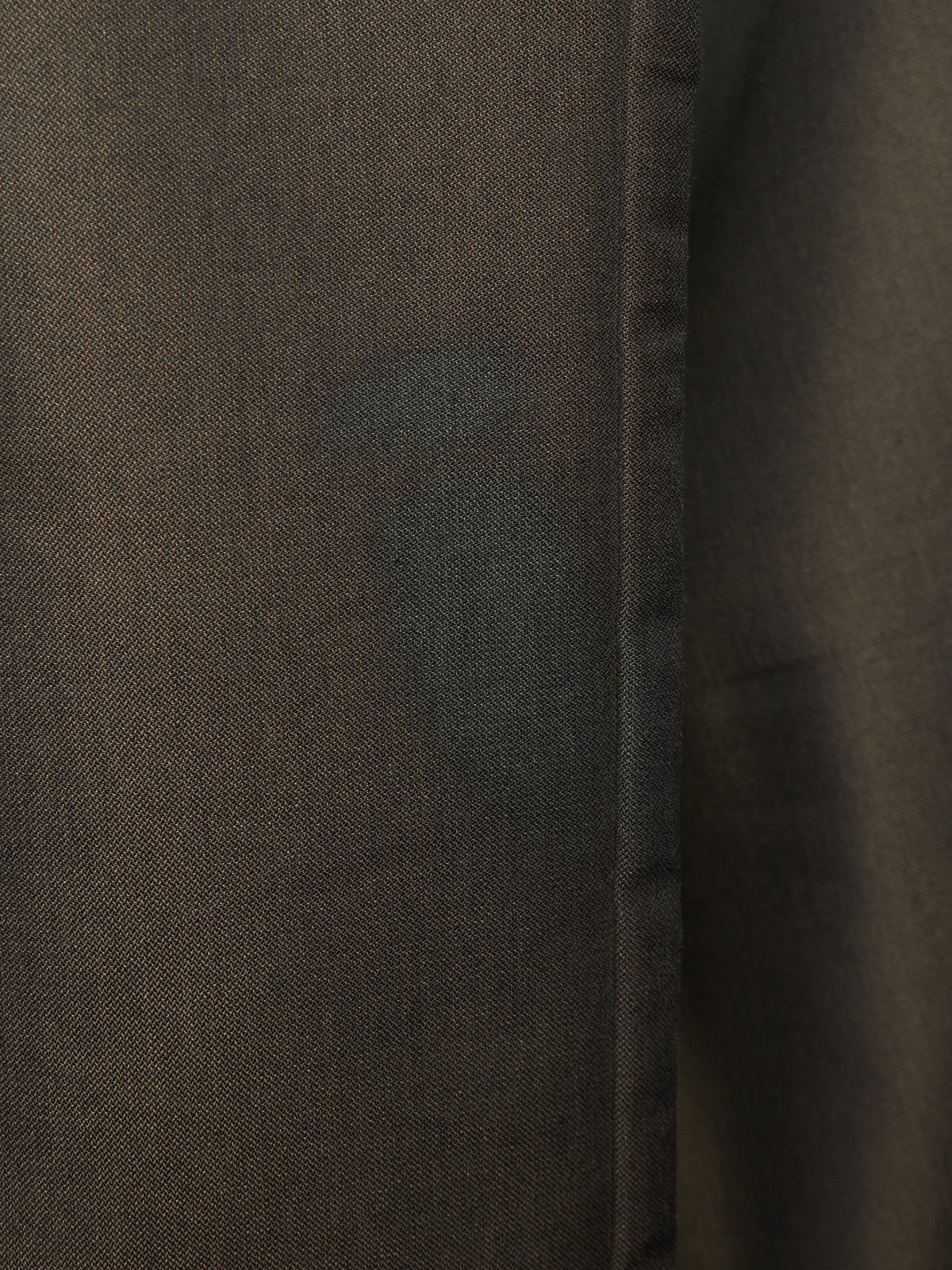 Close-up of a dark brown textured fabric with a visible vertical seam.