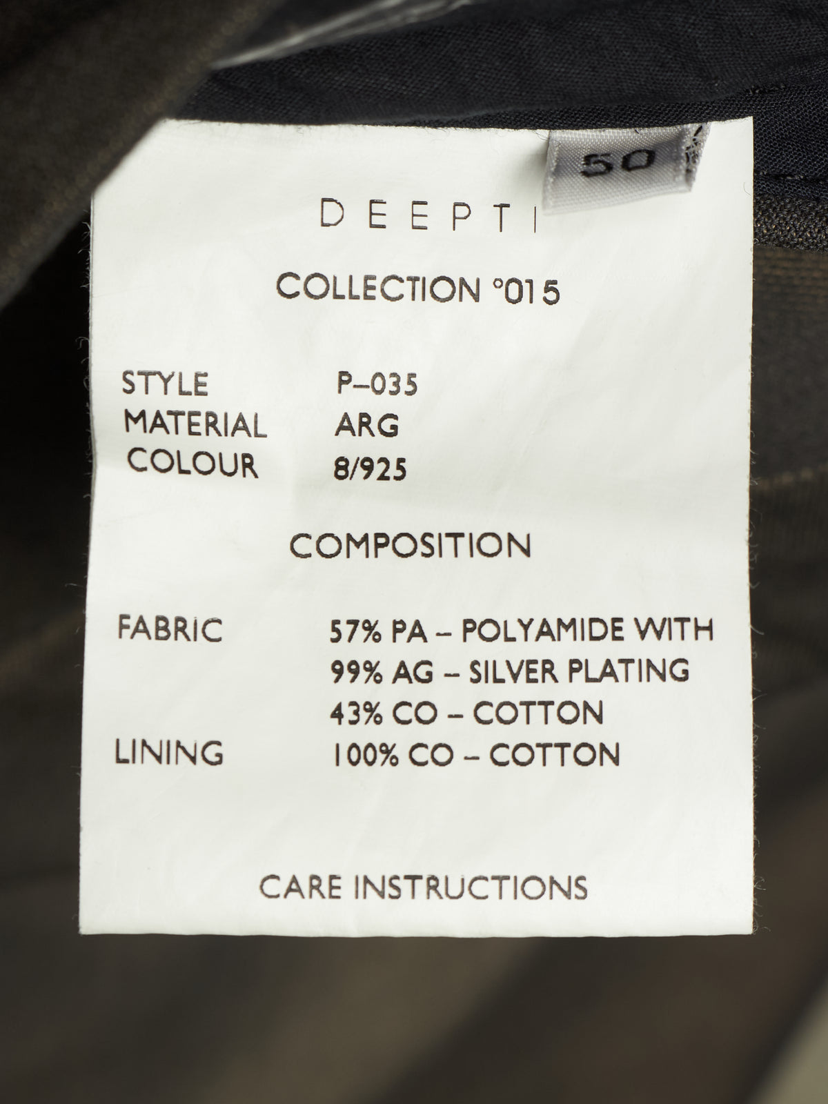 A close-up of a white fabric care label showing product details including 'DEEPTI', 'COLLECTION 015', 'STYLE P-035', 'MATERIAL COLOUR ARG 8/925', and composition/fabric/lining information, photographed against dark clothing fabric.