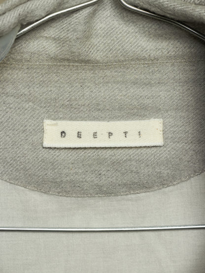 Close-up of the inside collar of a light gray woven garment on a metal hanger, showing a white fabric brand label that reads 'DEEPTI'.