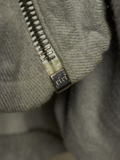 Close-up of a gray textured fabric zipper with a square metal pull tab engraved with the brand name 'cct'.