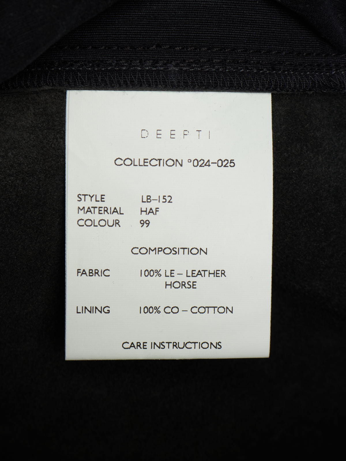 A white paper size and care label from the brand DEEPTI, showing details for collection '024-025' style LB-152, placed on the inside of a black garment.