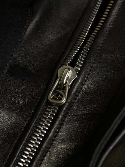 Close-up of a black leather zipper with a polished silver metal pull tab.