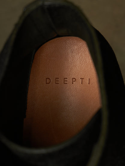 Close-up of the interior insole of a black shoe, showing the brand name 'DEEPTI' embossed on a tan leather footbed.