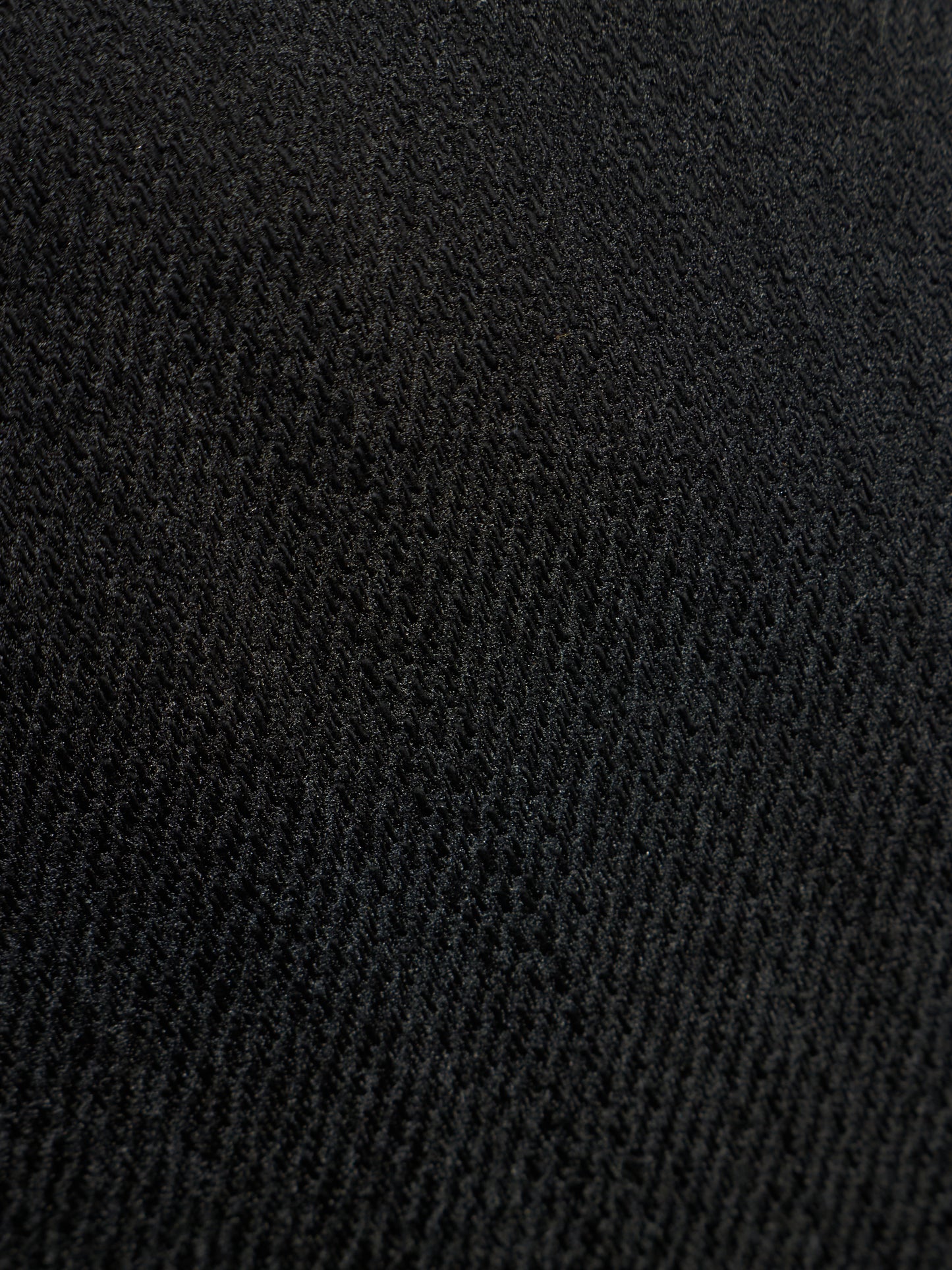 A close-up texture shot of a black ribbed knit fabric, showing the detailed weave pattern.
