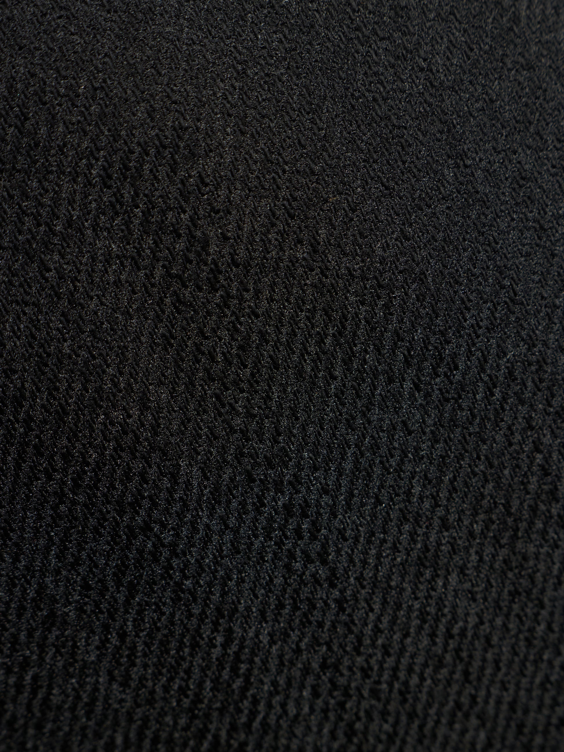 A close-up texture shot of a black ribbed knit fabric, showing the detailed weave pattern.
