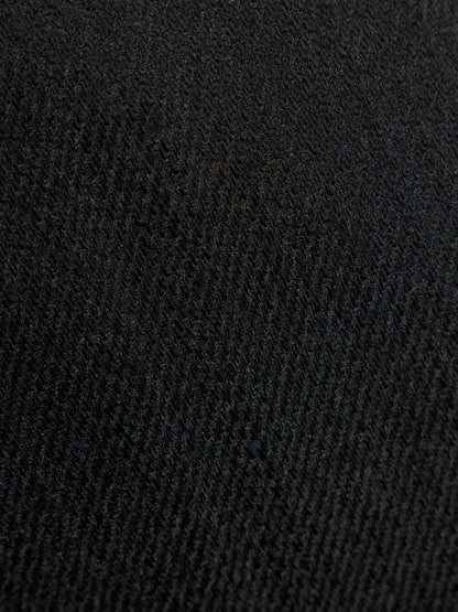 A close-up texture shot of a black ribbed knit fabric, showing the detailed weave pattern.