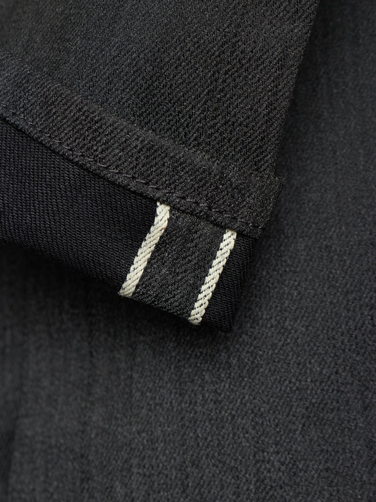 Close-up of a dark charcoal gray fabric cuff showing a double white contrast stitching detail.