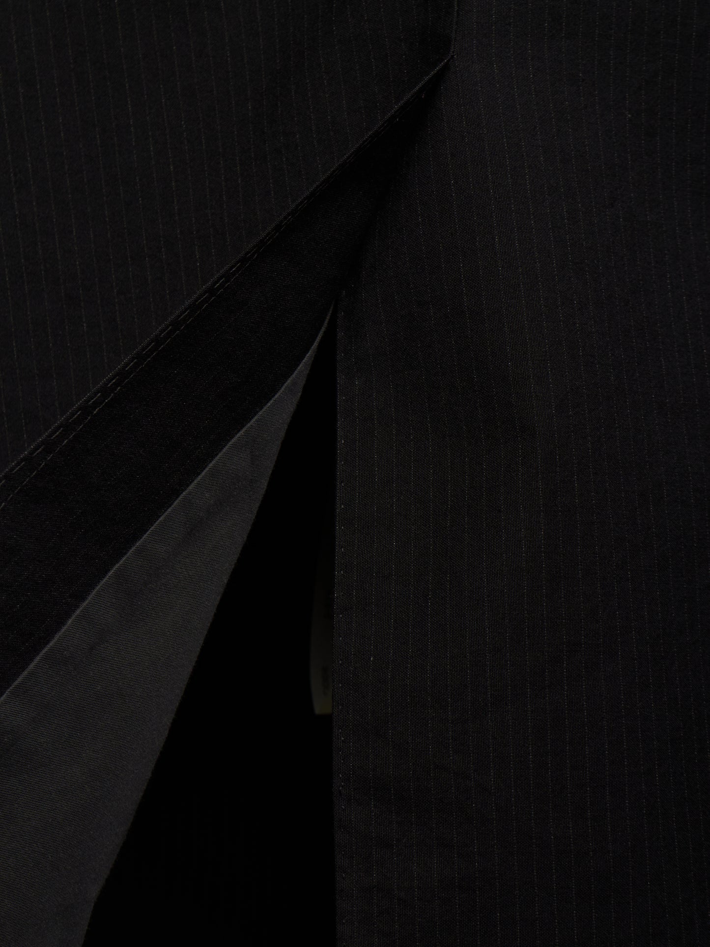 Close-up of a black pinstriped fabric garment, showing the texture and a diagonal fold or opening.