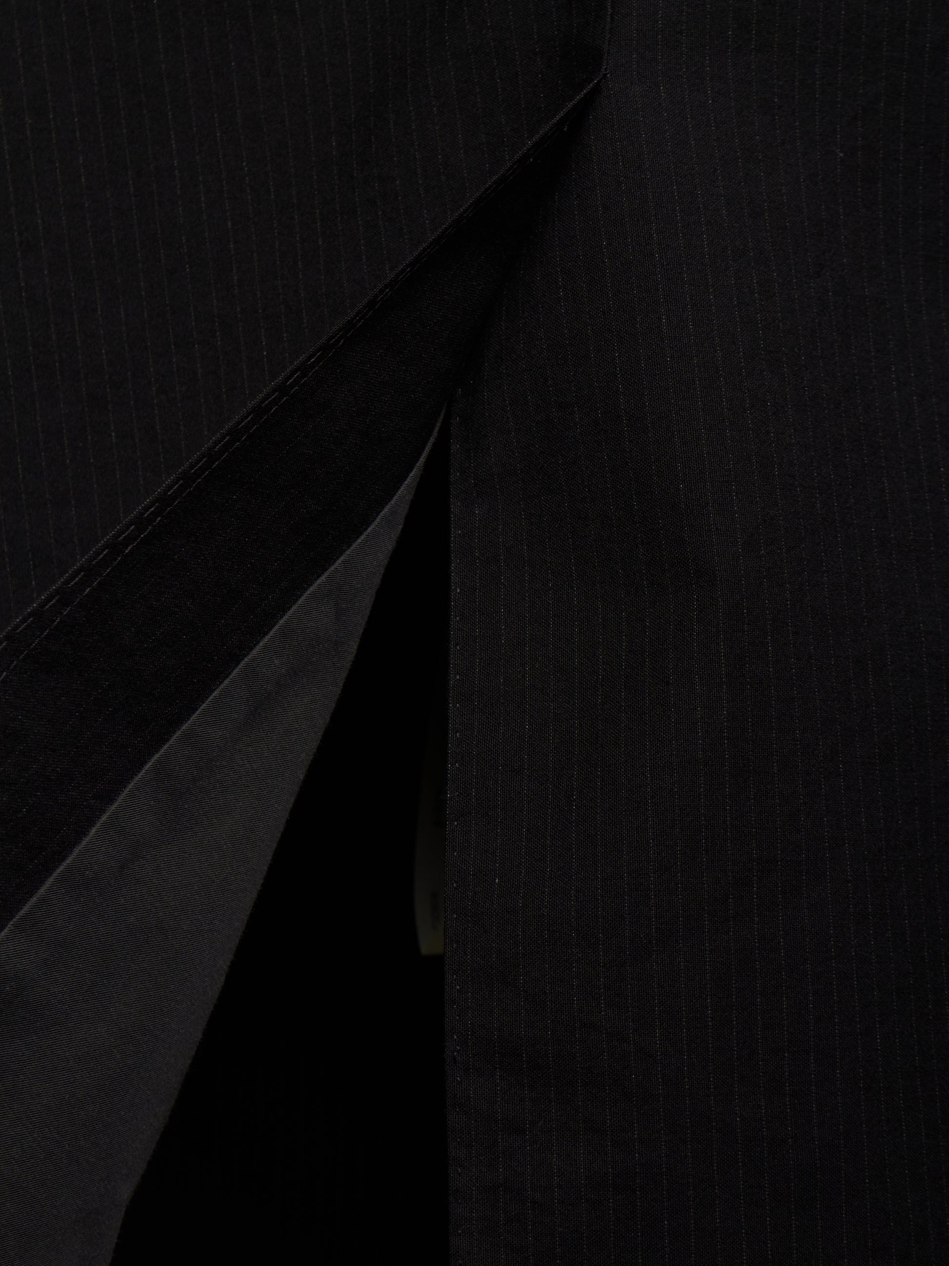 Close-up of a black pinstriped fabric garment, showing the texture and a diagonal fold or opening.