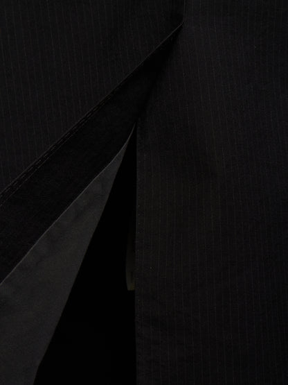 Close-up of a black pinstriped fabric garment, showing the texture and a diagonal fold or opening.