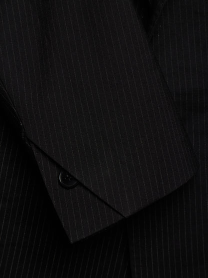 Close-up of a black pinstriped suit jacket, showing the fabric texture and a buttoned cuff detail.