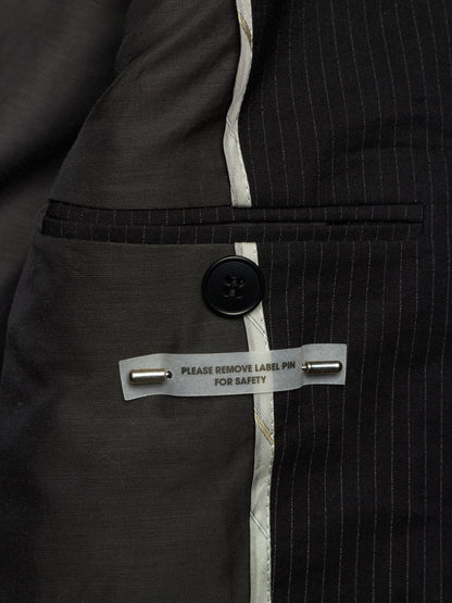 Close-up of a dark gray pinstripe suit jacket showing the interior lining, a buttoned pocket, and a safety pin label.