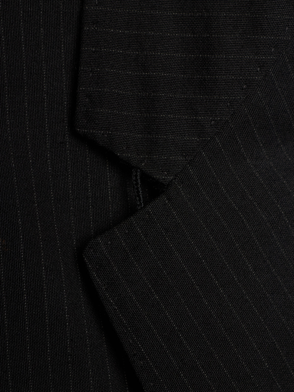 Close-up of a black pinstriped fabric, showing the fine vertical stripe pattern and texture.