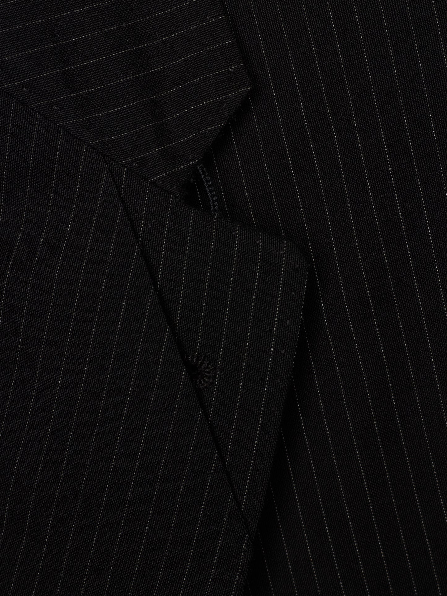 Close-up of a black pinstriped fabric, showing fine vertical white stripes on a textured material.