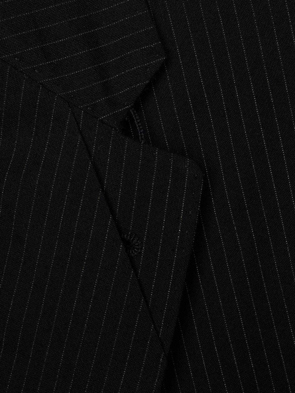 Close-up of a black pinstriped fabric, showing fine vertical white stripes on a textured material.