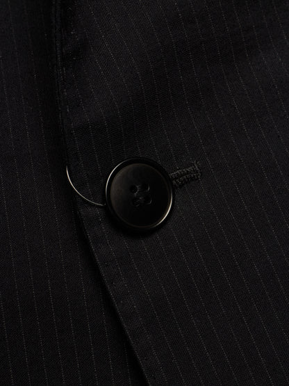 Close-up of a black pinstriped blazer fabric with a black button detail.