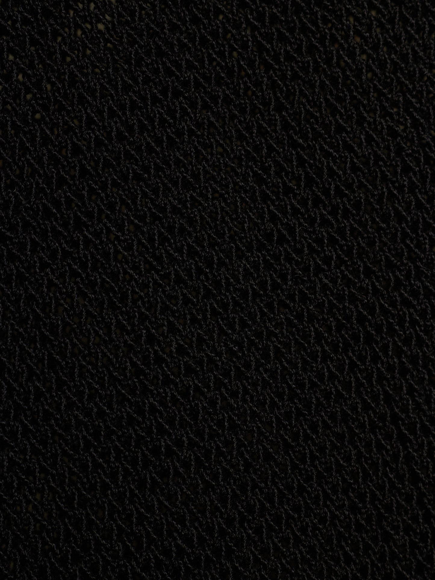 A close-up texture shot of a black woven fabric, showing a fine diagonal pattern.