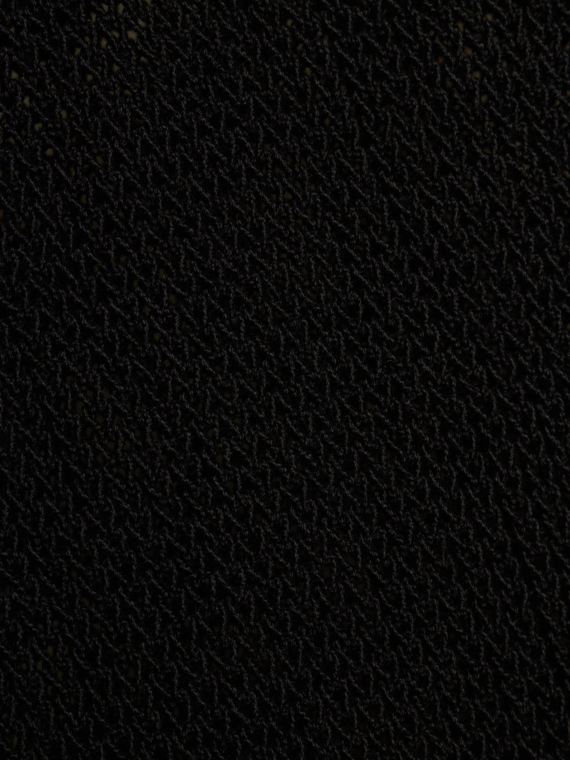 A close-up texture shot of a black woven fabric, showing a fine diagonal pattern.
