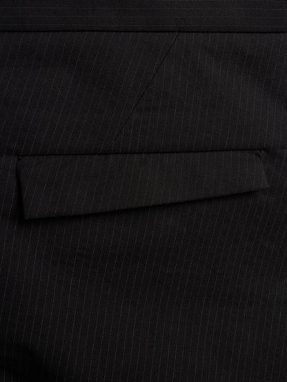 Close-up of a black pinstripe fabric surface with a folded pocket flap visible.