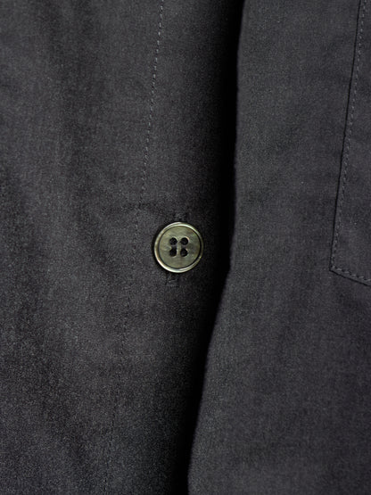 Close-up of a dark charcoal gray fabric jacket or coat with a single round metallic button on the front.