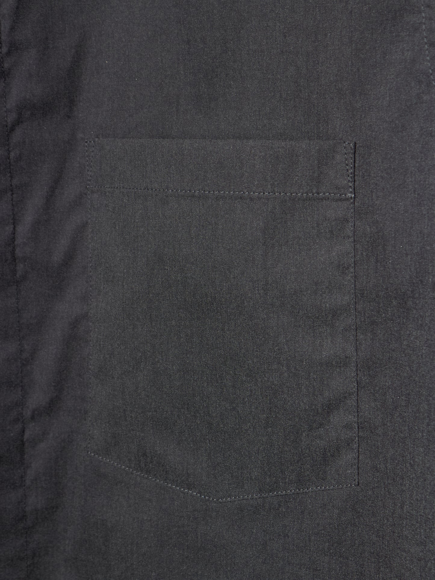 Close-up of a dark charcoal gray fabric garment showing a single rectangular chest pocket with neat stitching.