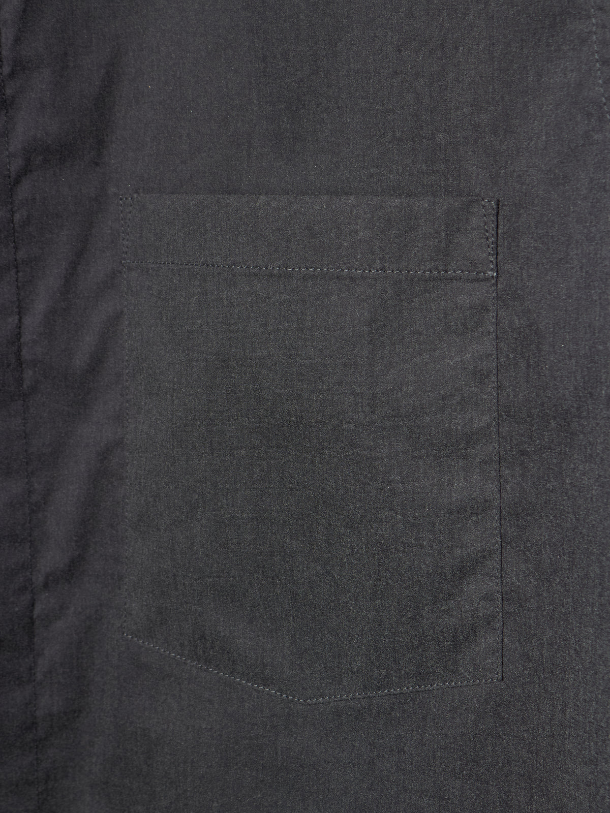 Close-up of a dark charcoal gray fabric garment showing a single rectangular chest pocket with neat stitching.