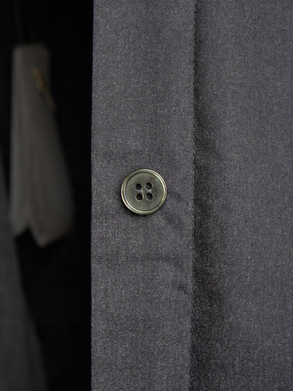 Close-up of a dark gray textured fabric garment with a single round metallic button on the front.