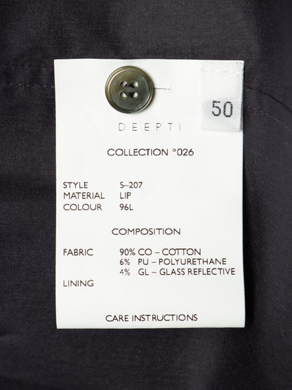 A white fabric care label with black text attached to a dark navy or black garment, featuring a metal button and a small white sticker marked 50.