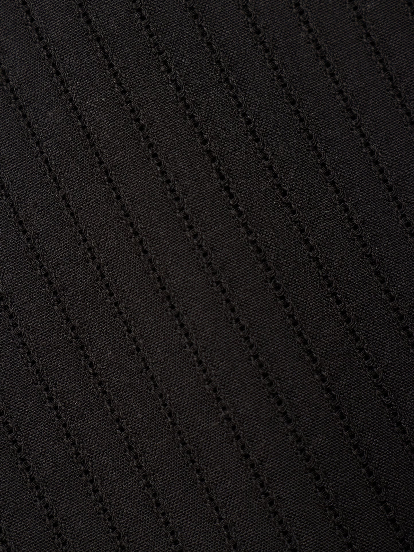 Close-up of a black textured fabric with diagonal ribbed or waffle-like stitching.