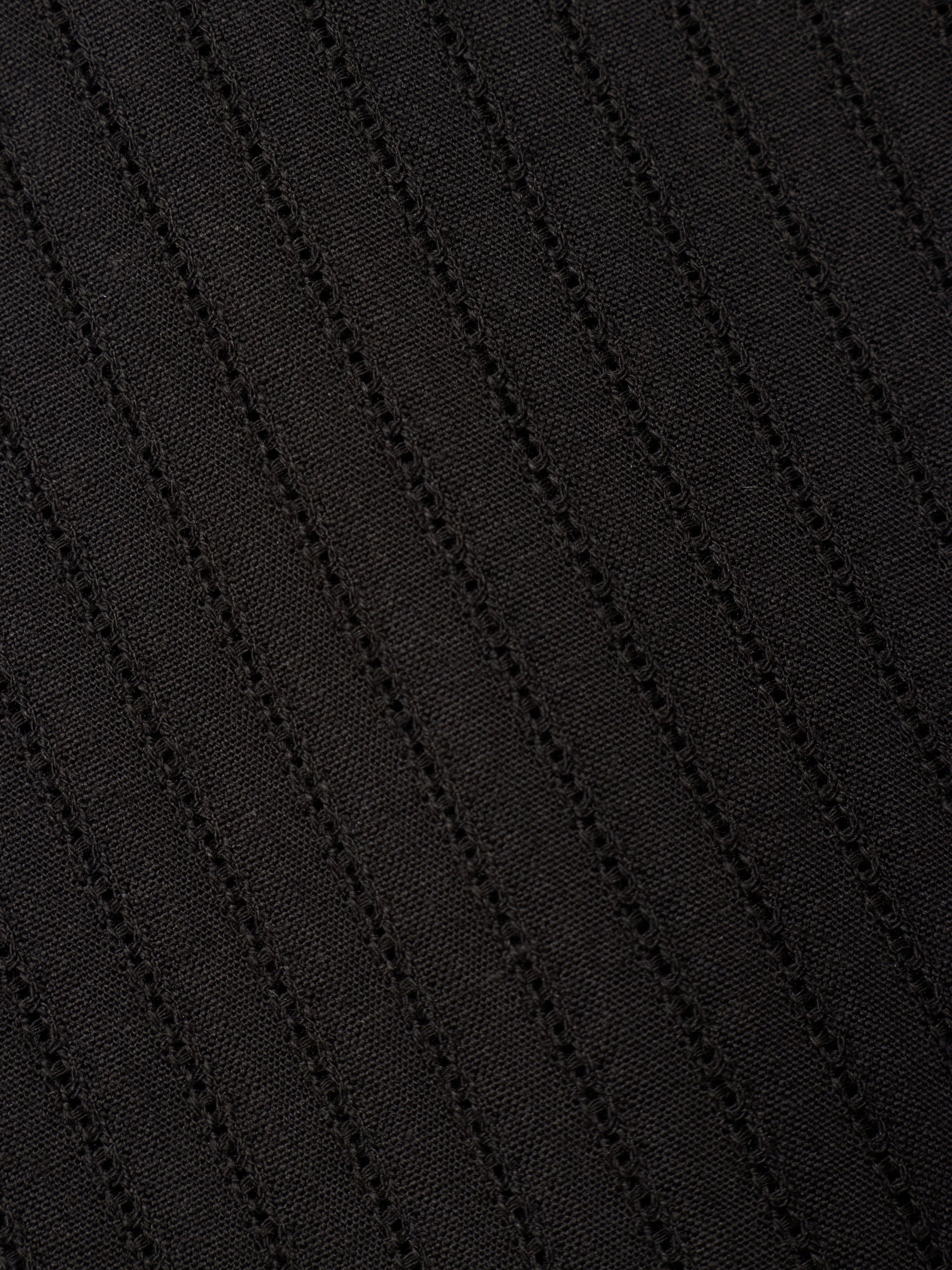 Close-up of a black textured fabric with diagonal ribbed or waffle-like stitching.
