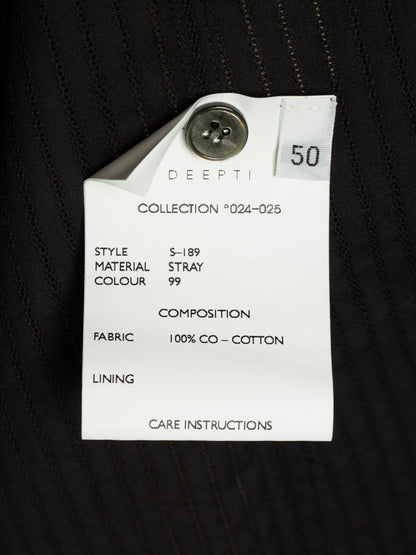 A close-up of a white paper garment tag attached to a black pinstriped fabric garment. The tag is printed with details including 'DEEPTI', 'COLLECTION *024-025', 'STYLE S-189', 'MATERIAL STRAY', 'COLOUR 99', 'FABRIC 100% CO - COTTON', and 'CARE INSTRUCTIONS'.