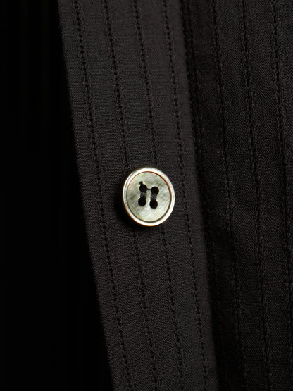 Close-up of a black pinstriped shirt with a round mother-of-pearl button with a gold-tone metal rim.