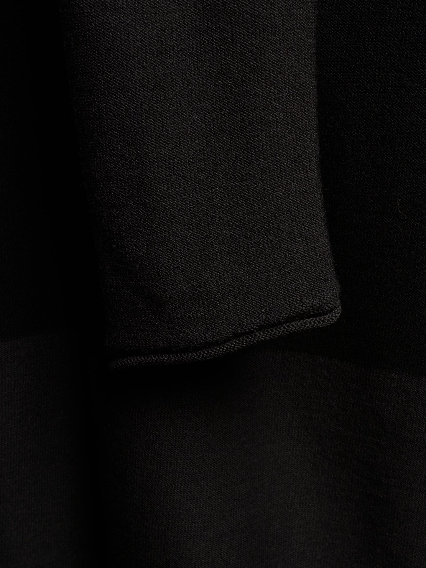 Close-up of a black knit fabric with a folded cuff showing the fine knit texture.