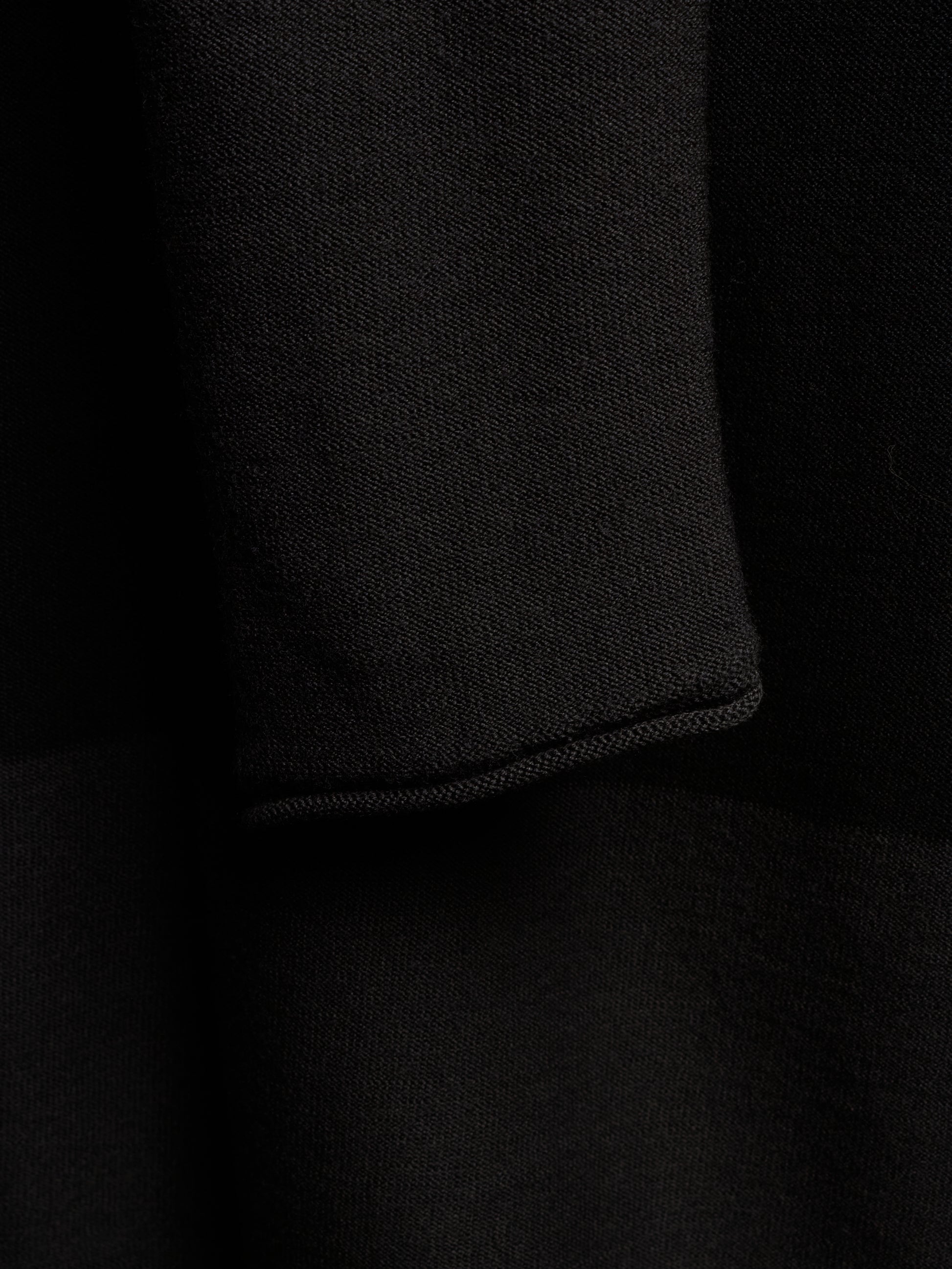 Close-up of a black knit fabric with a folded cuff showing the fine knit texture.